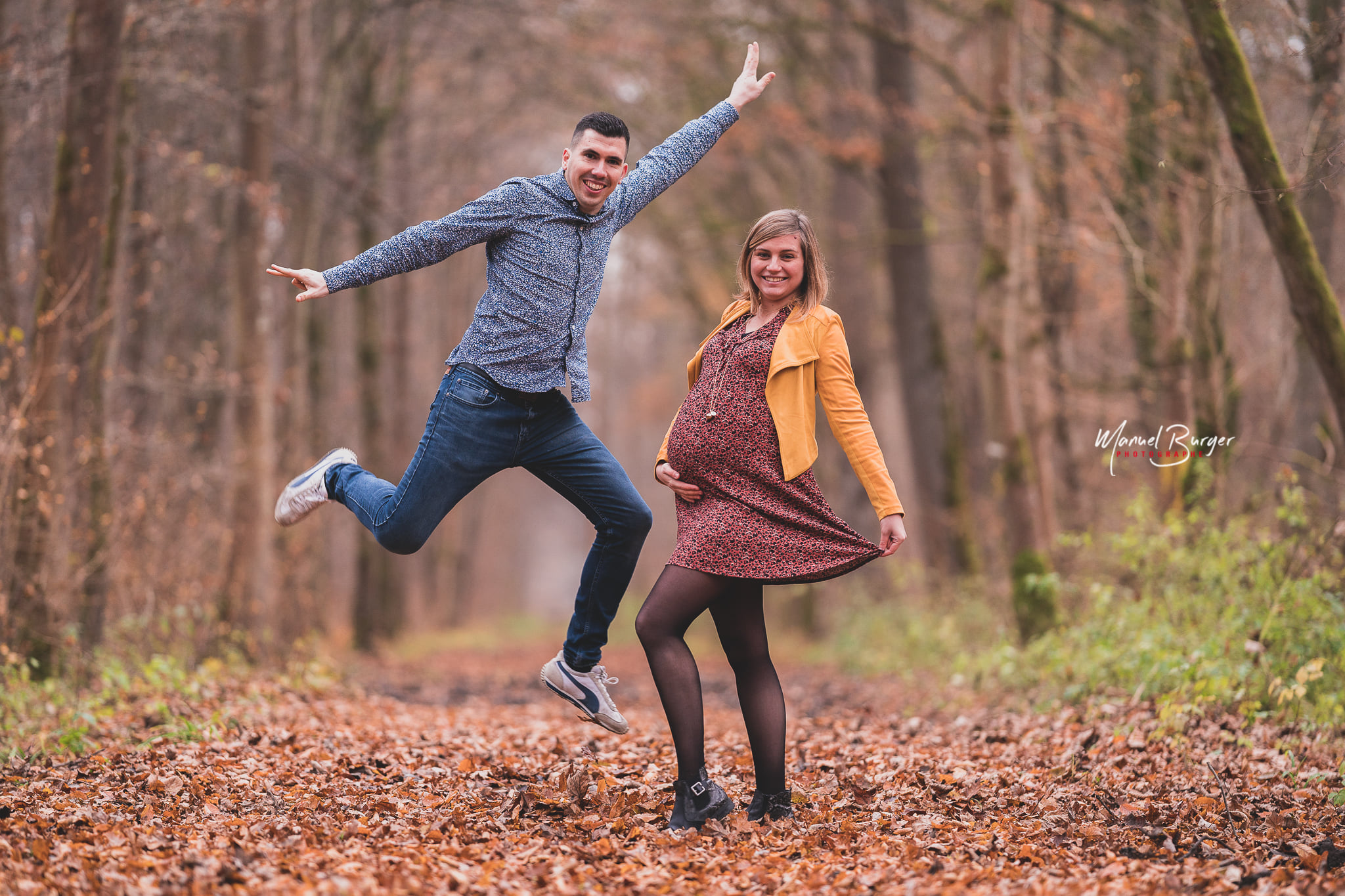 Instant de joie et saut spontané du futur papa à côté de la femme enceinte lors d'un shooting grossesse joyeux dans les environs de Sélestat.